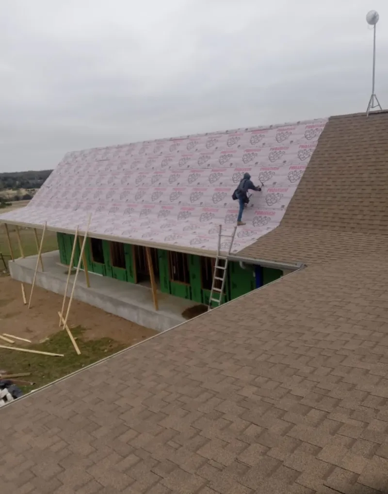 Worker preparing underlayment for a metal roof installation in New Ulm